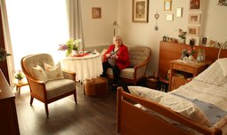 Gemütlich eingerichtetes Altenheim-Zimmer und einer älteren Dame beim Stricken | © Susanne Wagner